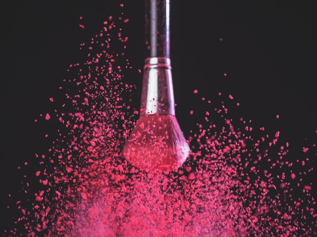 makeup-brush-with-pink-powder-explosion-on-black-background-min